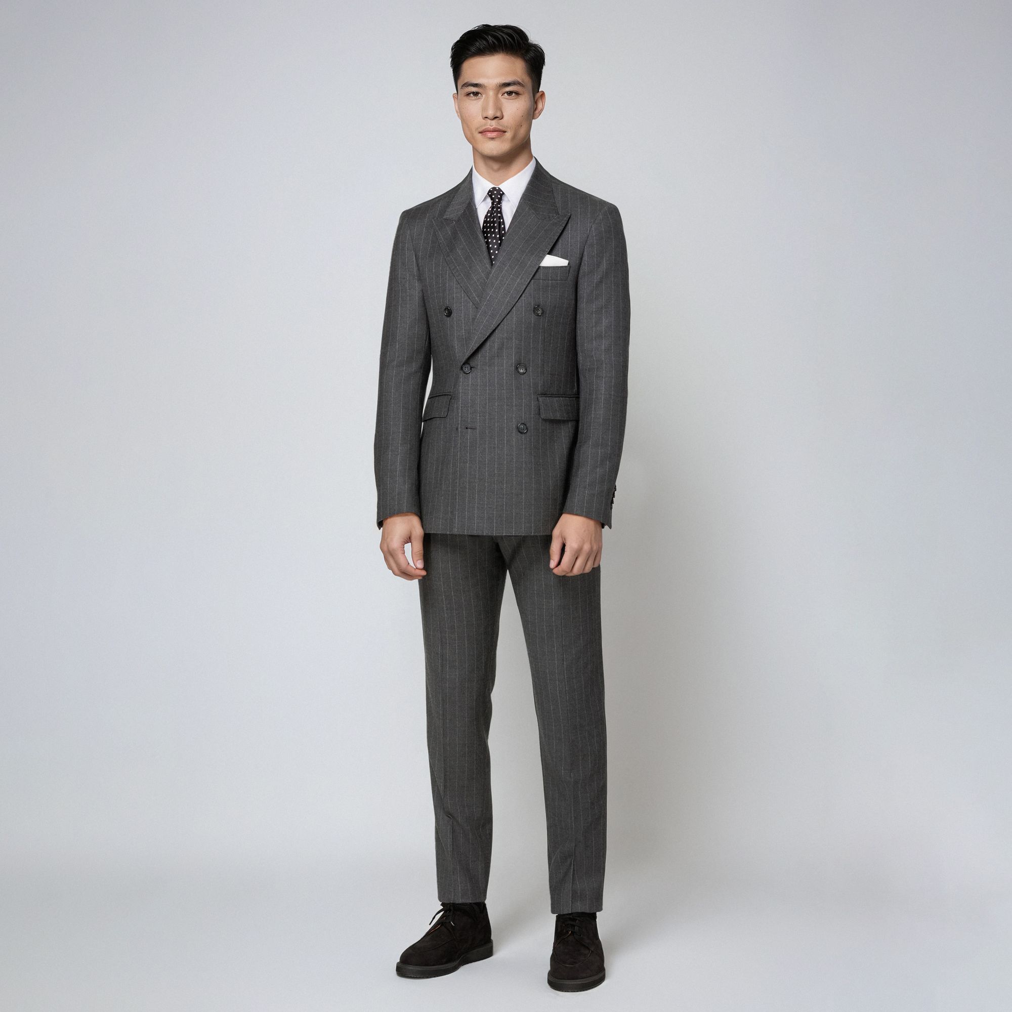 Άνδρας με total look Elio Evan: γκρι ριγέ μάλλινο σταυρωτό κοστούμι, λευκό πουκάμισο και γραβάτα.