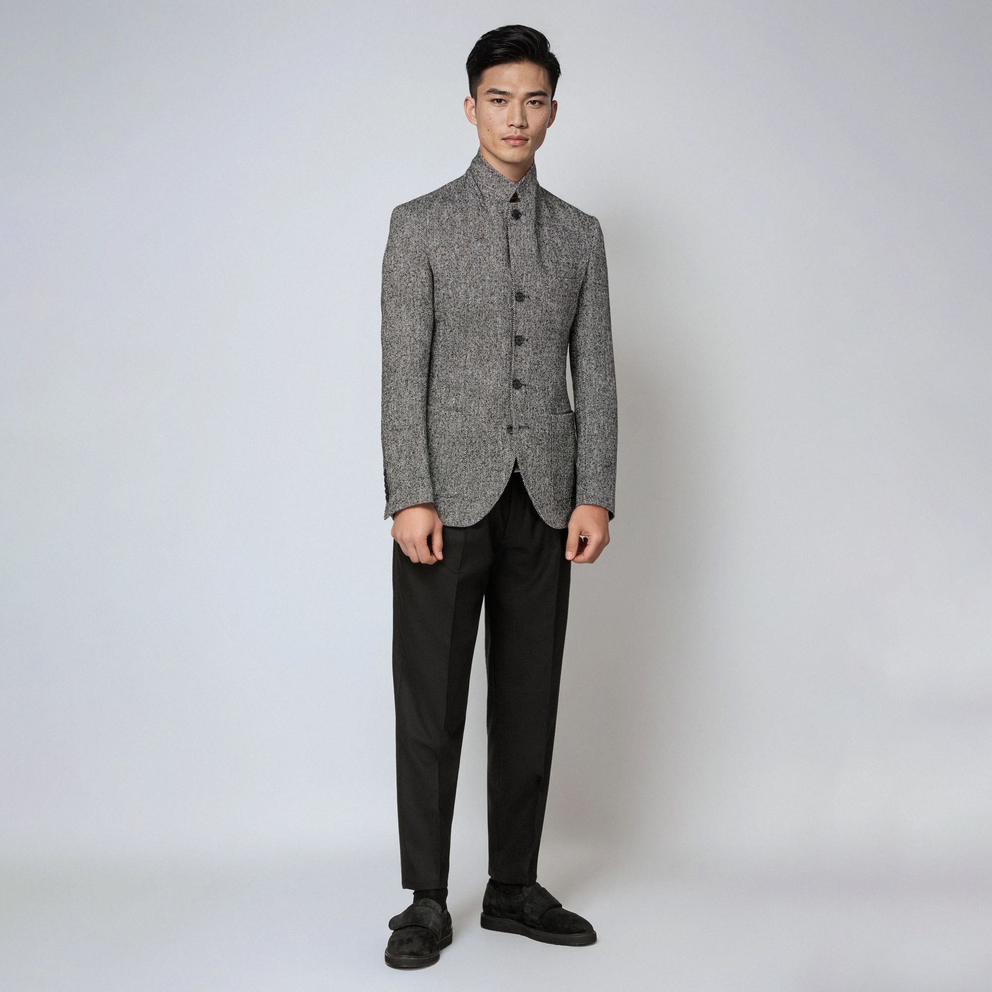 Άνδρας με total look Elio Evan: γκρι bouclé σακάκι με όρθιο γιακά και μαύρο παντελόνι.