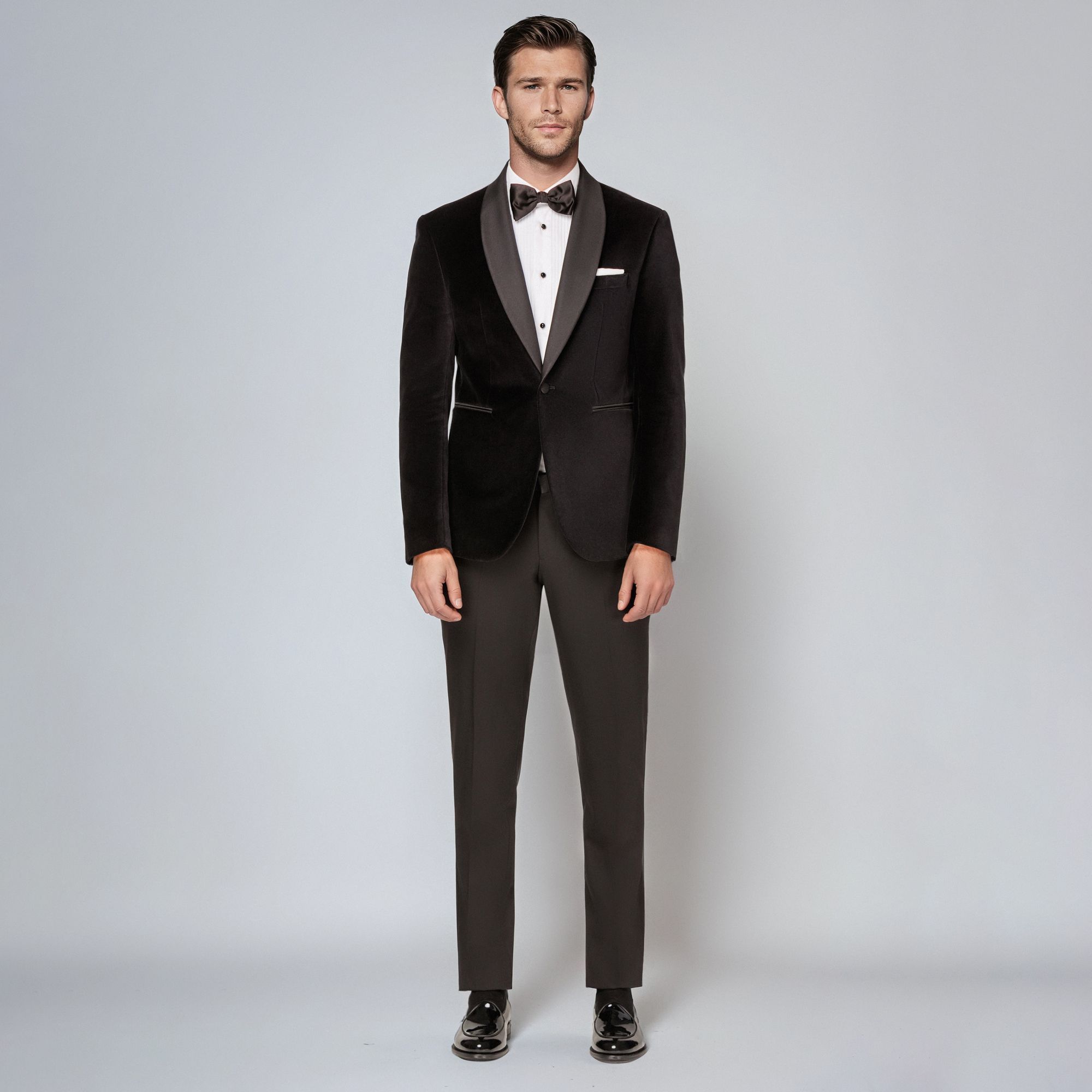 Άνδρας με total look Elio Evan: μαύρο βελούδινο tuxedo σμόκιν με σατέν πέτο, λευκό πουκάμισο και παπιγιόν.