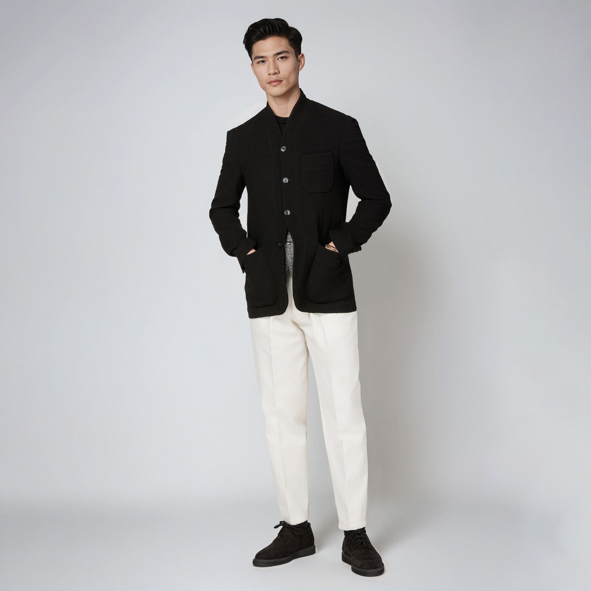Άνδρας με total look Elio Evan: μαύρο minimal μάλλινο σακάκι coreana με shawl-style γιακά και λευκό παντελόνι.